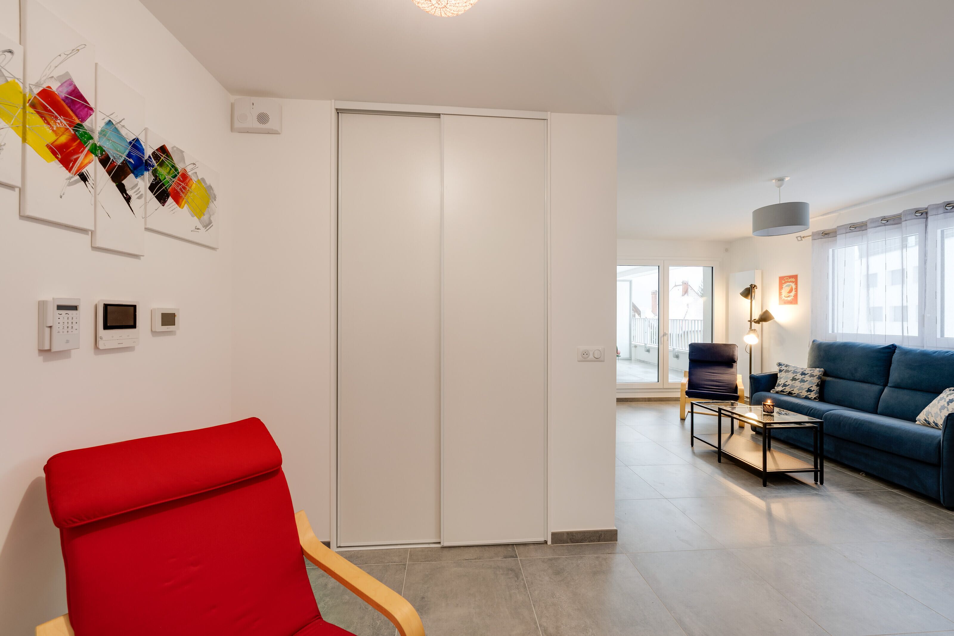 Una sala de estar moderna con un sillón rojo, un sofá azul y una mesa de centro.