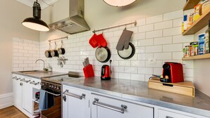 A modern kitchen with white cabinets, a stainless steel sink, and a built-in oven.