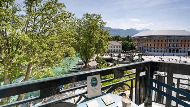 A riverside view with a bridge, trees, and a historic building in the background.