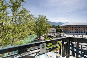 Une vue sur la rivière, avec un pont, des arbres et un bâtiment historique en arrière-plan.