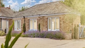 A stone building with a tiled roof, large windows, and a gravel driveway. - 5* Luxurious 1 bed self-catering cottage, 20mins from North&South Cornish coasts (Truro)