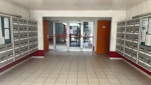 Un atrio con pavimento piastrellato, ingresso con porta in vetro e armadietti su entrambi i lati.