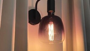 Una lámpara de pared con bombilla de vidrio transparente y estructura de metal negro.