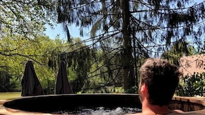 Un jacuzzi con vista a árboles y un muro de piedra.