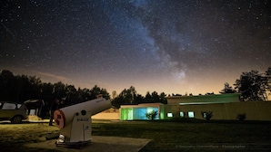 Un telescopio instalado al aire libre con una vista despejada de la Vía Láctea.
