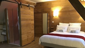 Un dormitorio con una cama, un armario de madera, una puerta corredera y una lámpara fijada a la pared.