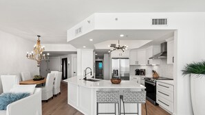 A modern kitchen with white cabinetry, a central island, and a chandelier. - Ocean Aire Gulf Front Condo, Resort, Pool (Destin)
