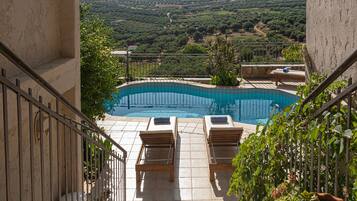 Una piscina con dos sillas de descanso y un muro de piedra.