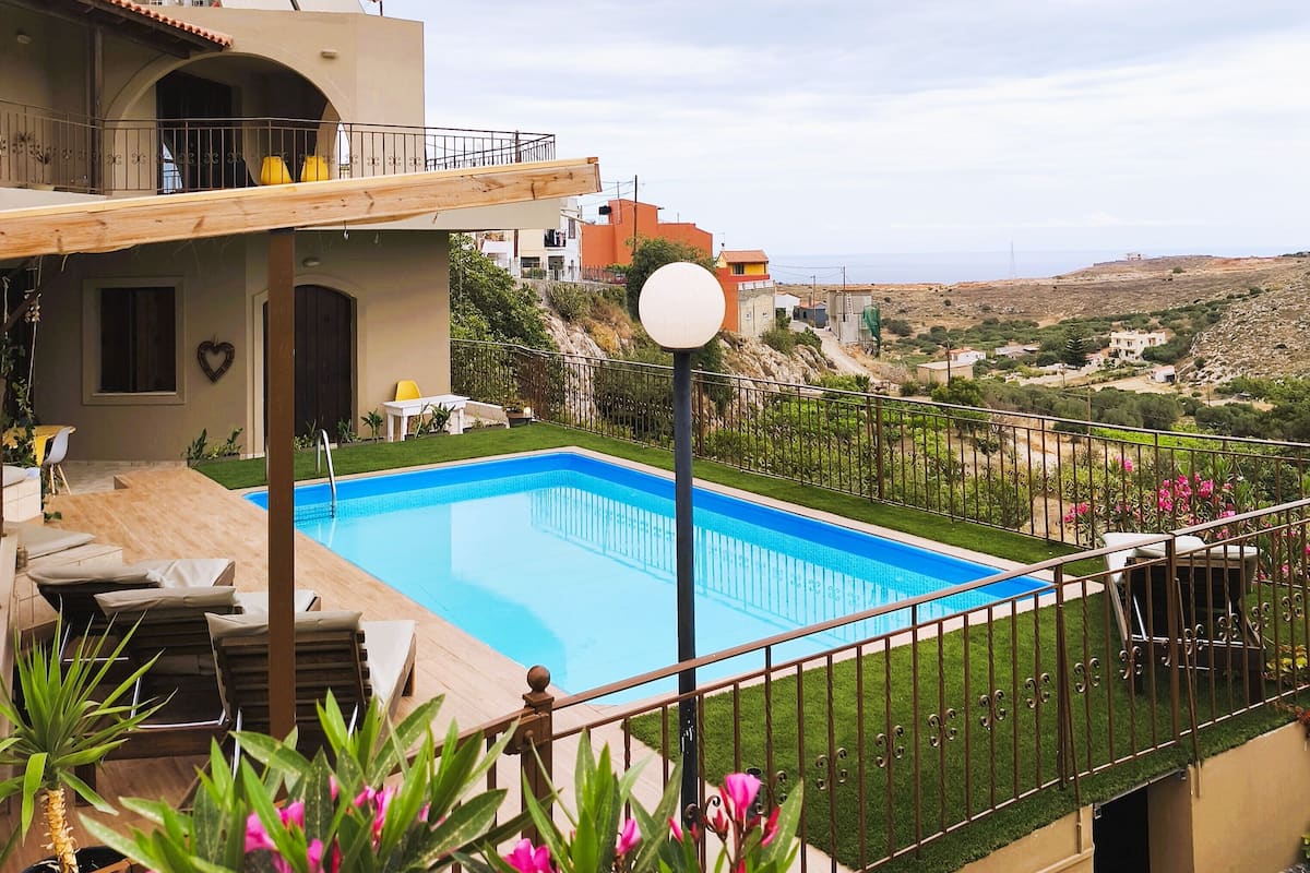 Una piscina con vistas al campo, un balcón con mobiliario exterior y un jardín bien cuidado.