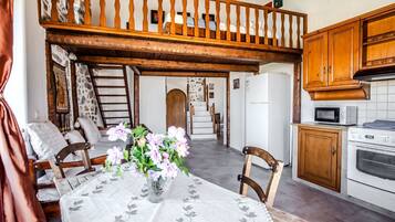 A cozy kitchen with wooden cabinets, a dining table with chairs, and a balcony with a wooden railing.