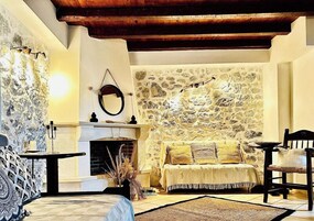 A cozy room with a stone wall, a fireplace, a sofa, and a dining table.