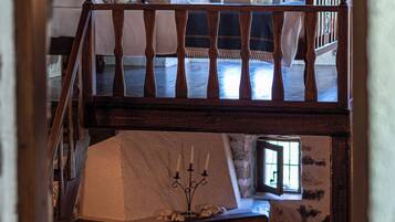 A rustic room with a wooden staircase, a stone fireplace, and a bed with a pillow.