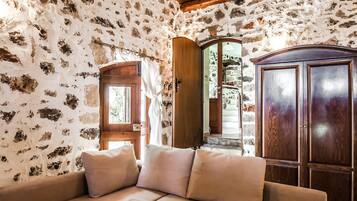A room with a wooden ceiling, a stone wall, a wooden cabinet, and a beige sectional sofa.