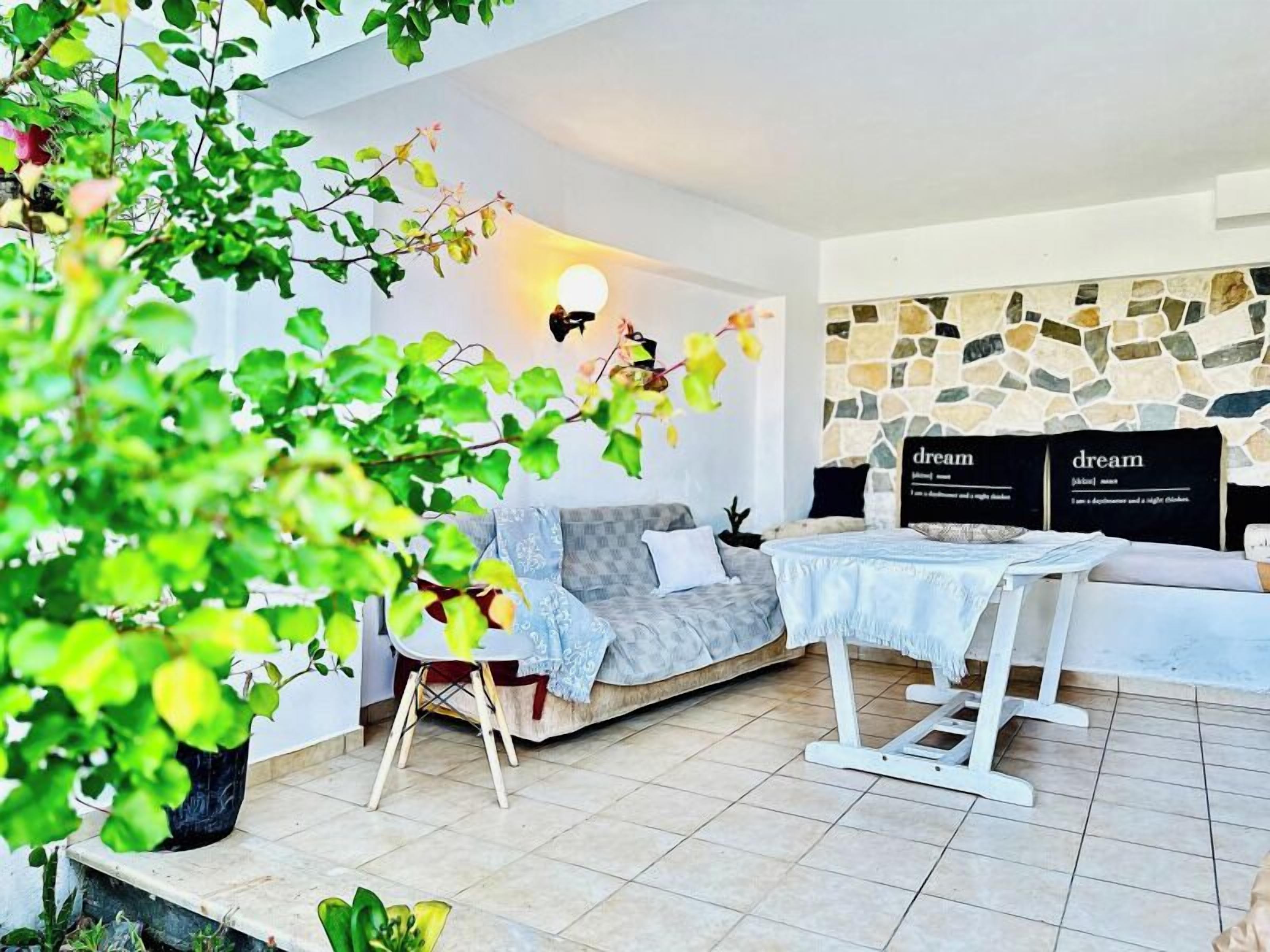 Una sala moderna con un sofá gris, una mesita pequeña y una pared de piedra decorada con carteles que dicen 'dream'.