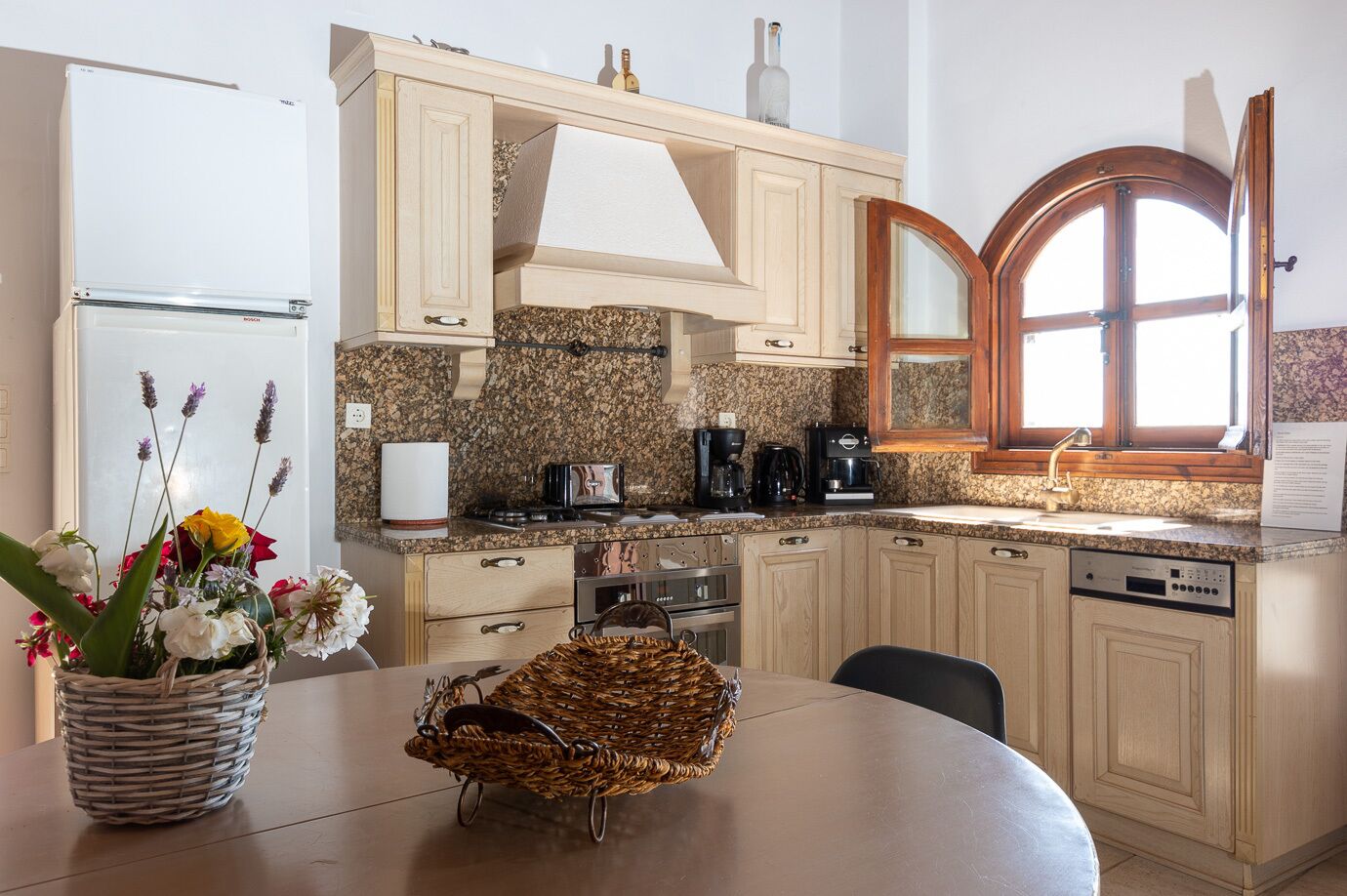 A kitchen with a granite countertop, a built-in oven, a coffee maker, and a dishwasher.