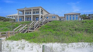 A large beachfront property with multiple levels, a staircase leading to the upper floors, and a beach in the foreground. - Gulf Front With Private Pool- Serenity Blue by Royal Destinations (Santa Rosa Beach)
