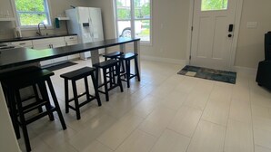 A modern kitchen with a central island, bar stools, and a large window. - Cozy, Modern Cabin with Private Hot Tub, Sleeps 6, Direct ATV Trail Access! (Hatfield)