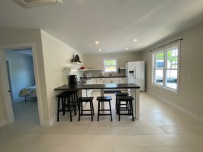 Una cocina moderna con una isla central, taburetes de bar y vistas al exterior.