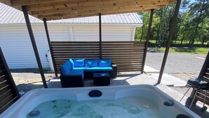 A hot tub with a wooden deck and blue outdoor furniture. - Cozy, Modern Cabin with Private Hot Tub, Sleeps 6, Direct ATV Trail Access! (Hatfield)