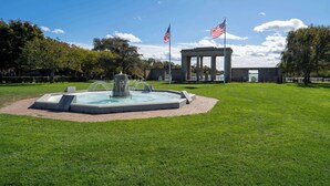 A well-maintained lawn with a central fountain, a gazebo, and two American flags. - Poppy’s Hampton House | 3BR + Bonus | Near Beaches & LIRR (Hampton Bays)