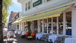 A restaurant with outdoor seating, tables covered with white tablecloths, and a large pumpkin decoration. - Poppy’s Hampton House | 3BR + Bonus | Near Beaches & LIRR (Hampton Bays)