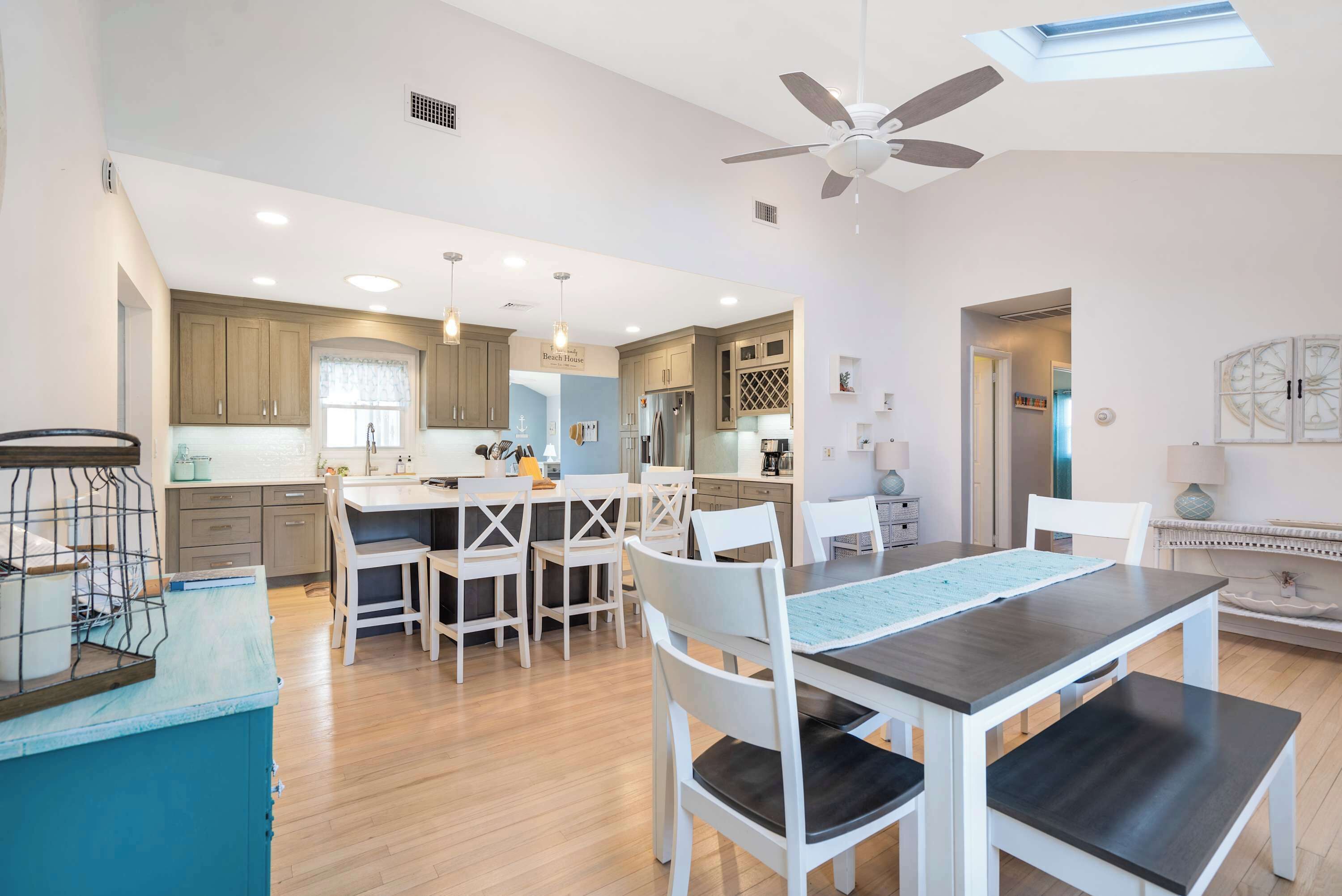 A modern kitchen with wooden cabinets, a central island with seating, and pendant lighting.