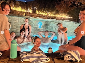 A group of people in a swimming pool with stone walls and a globe decoration.