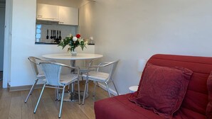 A compact living space with a dining area, kitchenette, and a red sofa.