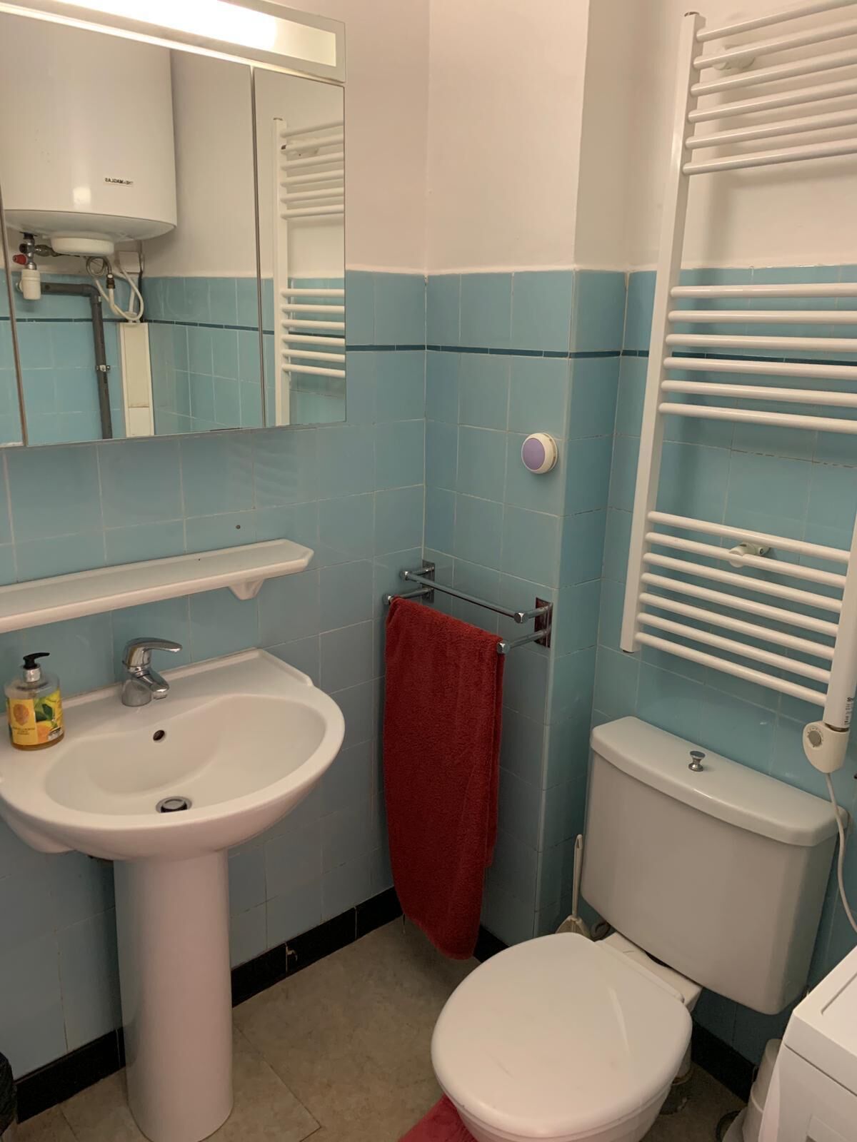 A bathroom with a white sink, a mirror, a toilet, and a towel rack.