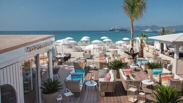 An outdoor seating area with umbrellas, lounge chairs, and a view of the sea.