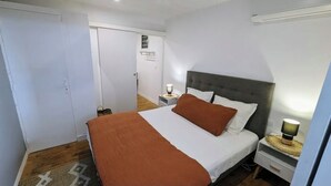 Een slaapkamer met een bed, nachtkastjes, een kledingkast en een deur.