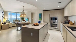 A modern kitchen with a central island, built-in appliances, and a dining area with a view.