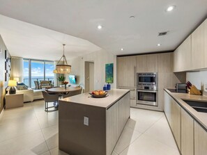 A modern kitchen with a central island, built-in appliances, and a dining area with a view.