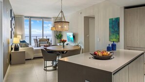 A modern kitchen with a central island, dining area with chairs, and a view to the outside.