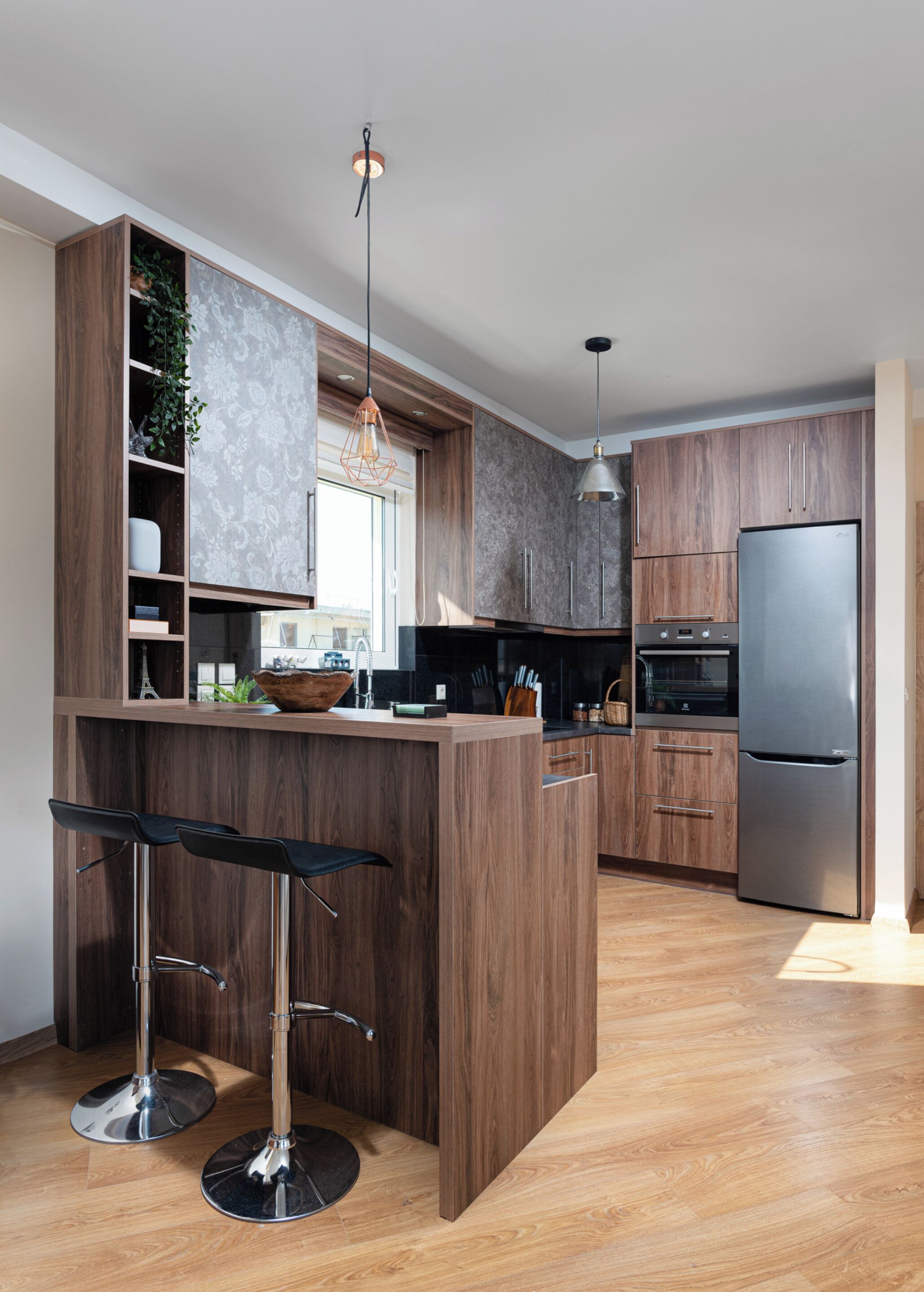 A modern kitchen with wooden cabinetry, a central island with bar stools, stainless steel appliances, and pendant lighting.
