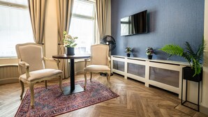 A room with two armchairs, a small round table, a television on the wall, and a radiator. - The Hogg House (Groningen)
