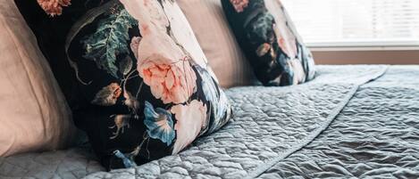 A bed with floral-patterned pillows and a quilted bedspread.