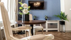 A dining area with a round table, chairs, and a TV mounted on the wall. - The Hogg House (Groningen)