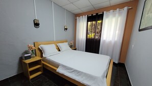 Ein ordentlich eingerichtetes Schlafzimmer mit einem Holzbett, einem Nachttisch, einem Beistelltisch und einem kleinen Teppich.
