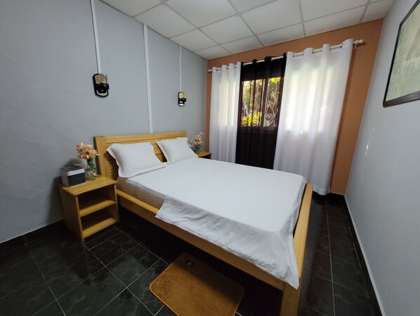 A neatly arranged bedroom with a wooden bed, a nightstand, a bedside table, and a small rug.