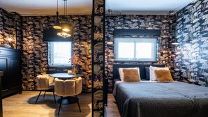 A room with a round dining table, chairs, a bed with pillows, and a window with blinds. - The Aquarium (Groningen)