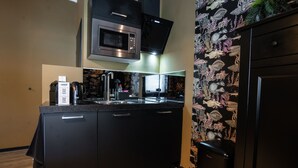 A modern kitchen with black cabinetry, a stainless steel microwave, and a built-in oven. - The Aquarium (Groningen)