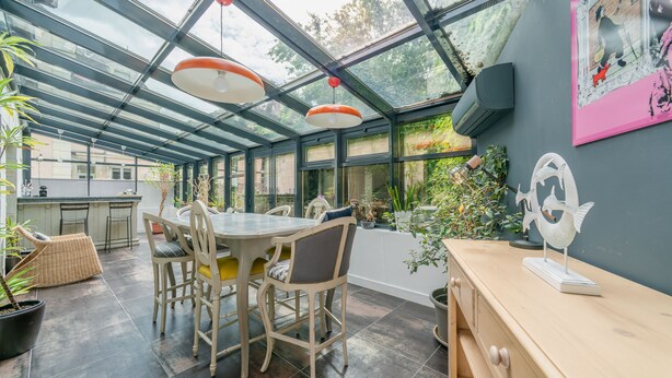 Une cuisine moderne avec un plafond en verre, des meubles en bois et des plantes en pot.