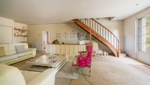 Un vaste espace de vie comprenant un escalier, un canapé, une table basse et un fauteuil.