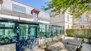 Une maison moderne avec de grandes fenêtres, une terrasse en bois et un jardin.