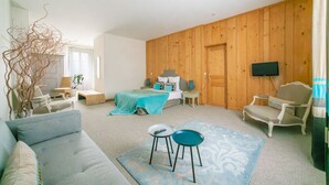 Une chambre moderne avec un lit, un canapé, une télévision et un mur en bois.
