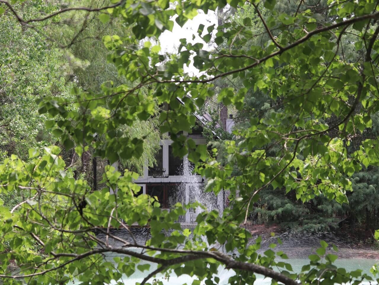 Una cascada en un área boscosa con una estructura al fondo.