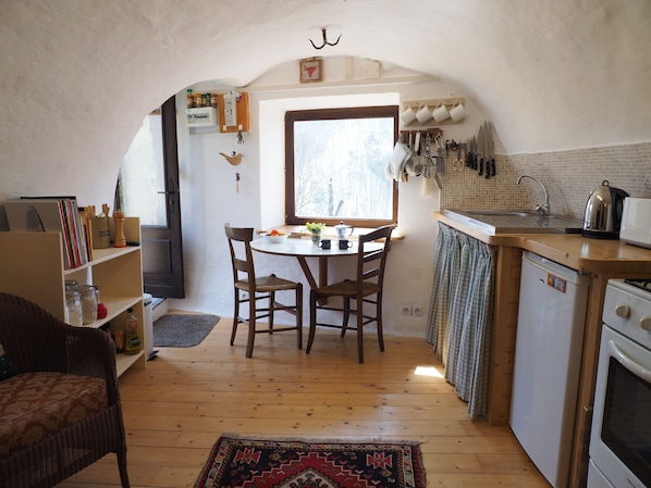Una cocina acogedora con pisos de madera, una mesa de comedor con sillas, un refrigerador y un lavamanos.