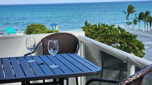 A balcony with a table and chairs overlooking the ocean.