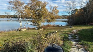 A lakeside view with a dock, a covered grill, and a stone pathway. - Cozy, ocean-side retreat (Sedgwick)